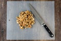ChefÃ¢â¬â¢s knife and a pile of raw walnuts on a plastic cutting mat, ready for baking Royalty Free Stock Photo